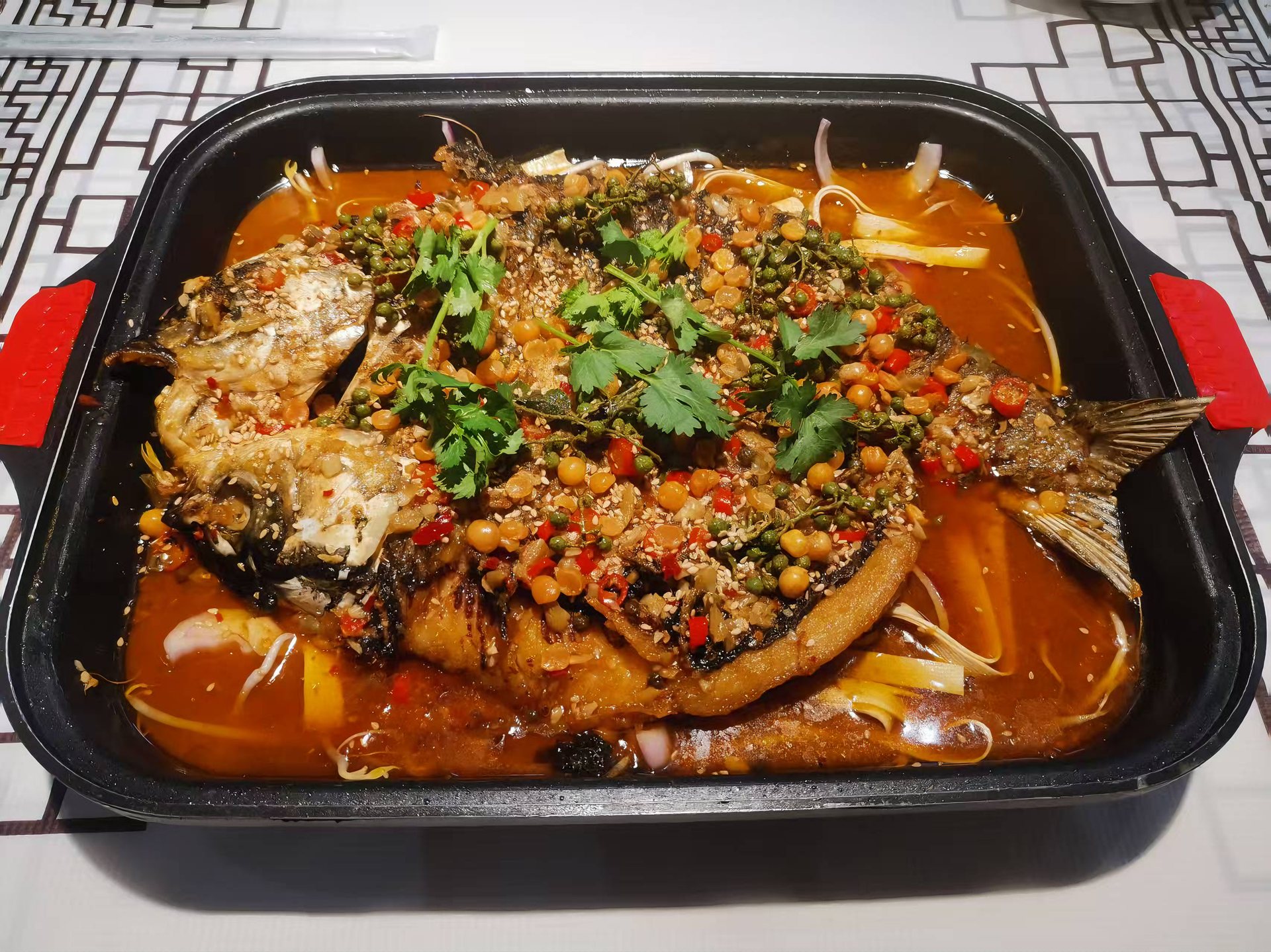 店内招牌烤鱼，铺满青花椒、红辣椒与白芝麻，红油环绕