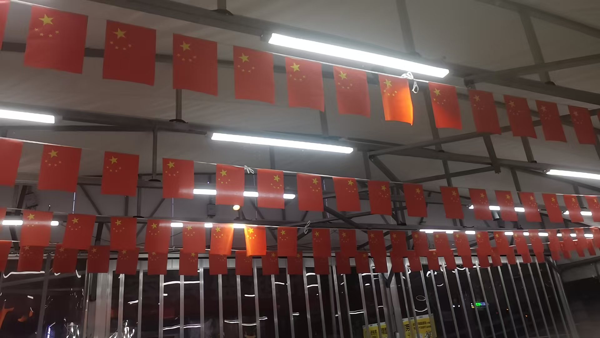 店外露天外摆区吊顶悬挂的成排国旗与照明灯管